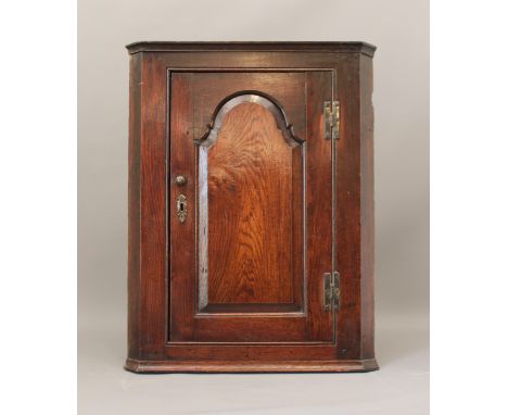 An 18th century oak hanging corner cupboard - of good colour, the ogee panelled door enclosing two shaped shelves, with the o