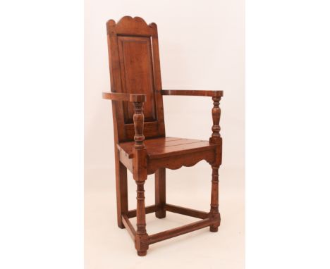 An early 18th century style oak open armchair - 20th century, the panelled back with scroll top rail, over swept arms on turn