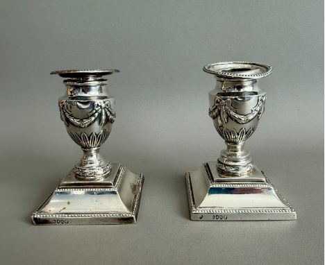 A pair of Victorian silver dwarf candlesticks - Rupert Favell, London 1883, with Adam style swagged and stiff leaf decoration