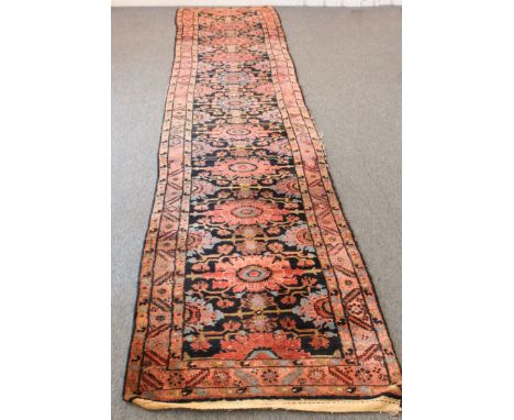 An antique Persian runner - with with red and blue floral medallions on a dark blue ground, within a red Herati border, 416 x