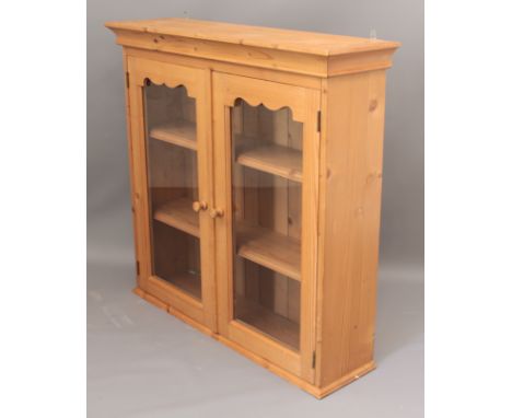 A pine wallhanging glazed cabinet - the cavetto cornice over two glazed doors enclosing two fixed shelves. (LWH 97 x 27 x 93c