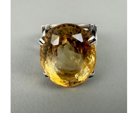 A white metal and citrine ring - unmarked (tests as silver), the large, 23 x 19mm fancy oval cut citrine in a flour claw sett