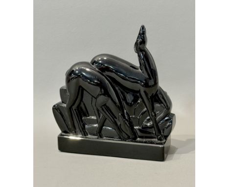 An Art Deco style black glass sculpture - depicting two deer amidst stylised foliage, on a platform base with bevelled edges,