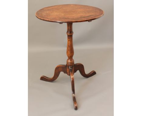 A George III oak tilt-top tripod table - the circular top on a slender turned baluster column to three swept supports, 53cm d