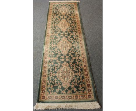A Persian-style wool runner - second half 20th century, with four ivory lozenge medallions on a green field with all over flo