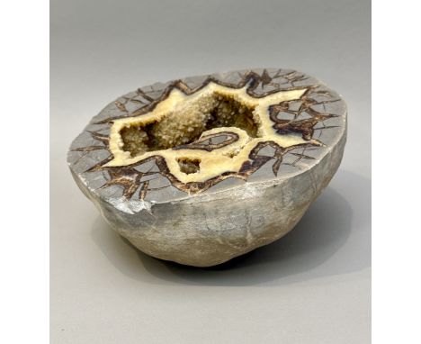 A large Septarian nodule / concretion mineral specimen - the cut half-geode with central calcite crystals within a jagged, to