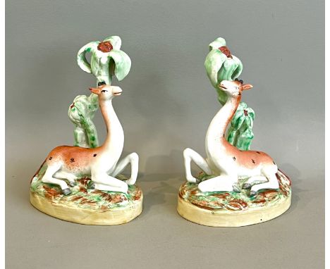 A pair of 19th century Staffordshire figures of giraffes - modelled lying beneath a palm style tree, on a naturalistic base, 