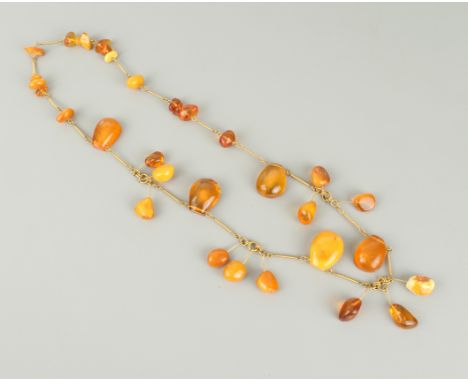 A vintage egg yolk and clear amber necklace - mid-20th century, the polished, naturalistically-shaped beads in a variety of s