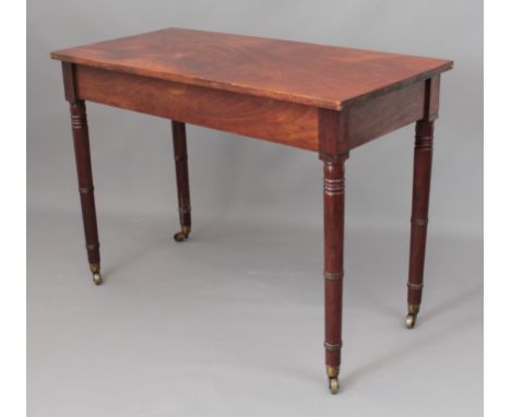 A 19th century mahogany side table - the rectangular top on ring turned legs with brass cup-castors. (LWH 100 x 46.5 x 71cm)