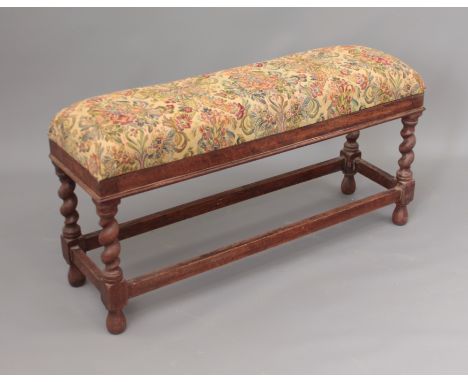 A rectangular oak stool - the high stuffover seat upholstered with tapestry-style fabric, the barleytwist supports united by 