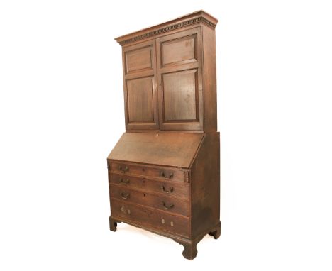 A George III oak bureau bookcase - the top and base section probably a marriage, the dentil cornice over a pair of two-panel 