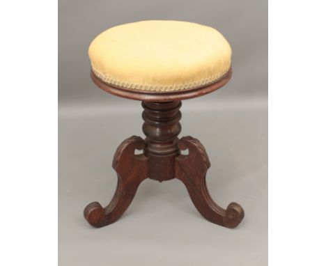 A William IV carved mahogany adjustable piano stool - the stuff over circular seat on a ring turned column, raised on three f