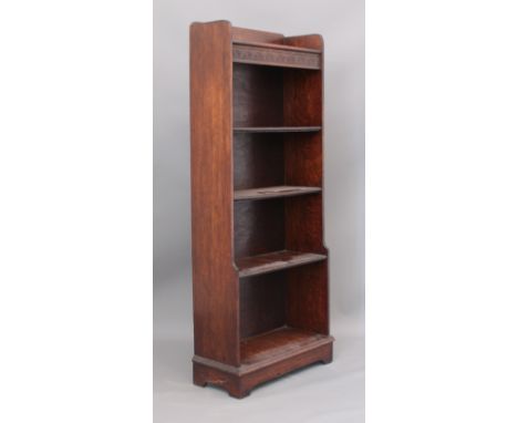 A stained oak freestanding bookcase - the three-quarter gallery top over a carved apron and three fixed shelves with beaded e