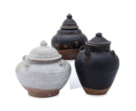 A GROUP OF THREE POTTERY JARS AND COVERS
12th-15th Century, a white glazed Sawankhalok squat jar and with four lugs and lotus