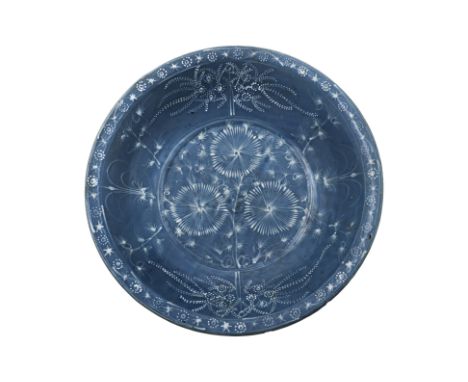 A LARGE SWATOW SLIP-DECORATED BLUE GROUND BOWL Ming Dynasty, with rounded sides and flat rim, decorated to the centre with th