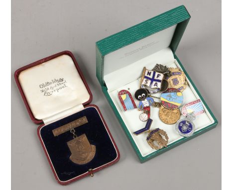 A quantity of enamel badges including Butlins, golly and military examples.