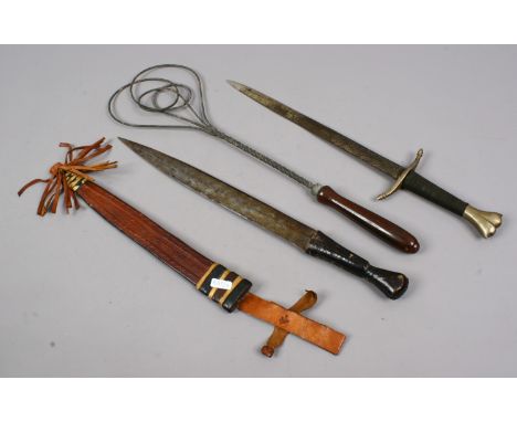 An African dagger with leather mounted grip and scabbard along with a rug beater and another decorative knife.
