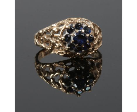 A 9 carat gold sapphire ring floriform set with 9 stones, pierced shoulders and textured band, size K 1/2 gross weight 2.5 gr