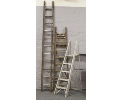 A pair of wooden step ladders, along with a aluminium step ladder and a double wooden ladder.