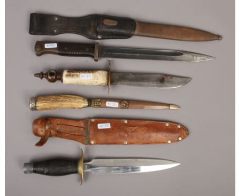 A German World War II bayonet in scabbard along with three other knives to include antler handled examples.