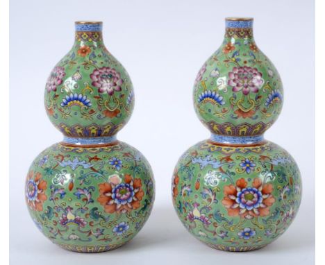 A pair of Chinese porcelain double gourd vases, decorated scrolling flowers and foliage in enamel colours, on a green ground,