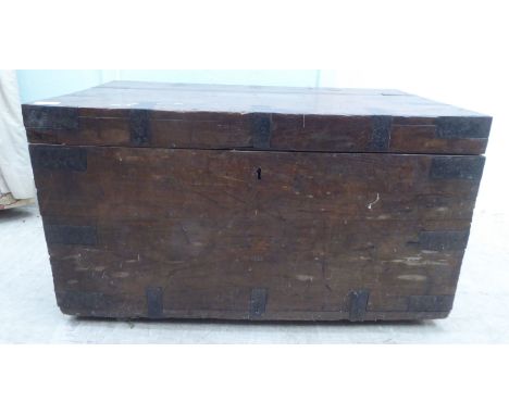 A late 19thC hardwood trunk with iron brackets and flank bail handles with an inscribed brass nameplate to the lid, enclosing