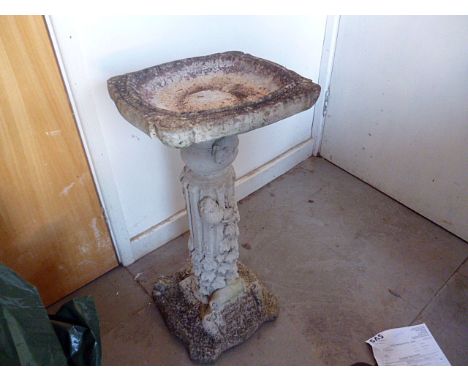 A stone composite bird bath, the column bass having mouse and vine decoration