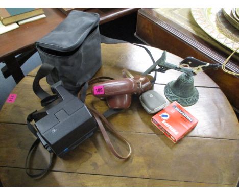 A Polaroid camera and case, a Halima camera and case with accessories, and a metal verdigris door bell with cow decoration