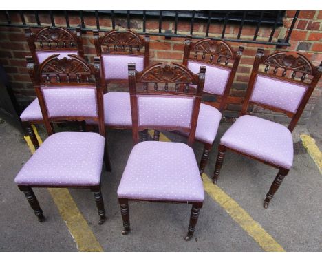 A set of six walnut dining chairs with carved crest rail supported on short spindles, upholstered backs and seats on turned f