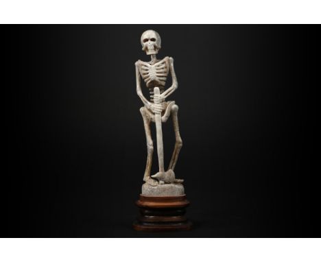 sculpture in bone depicting a skeleton with axe - on a wooden baseSculptuur in been met de voorstelling van een skelet met bi