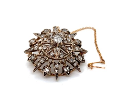AN ANTIQUE OLD CUT DIAMOND RADIATING STAR BROOCH WITH ATTACHED SAFETY CHAIN. THE PRINCIPLE OLD CUT DIAMOND IN A RAISED COLLEC