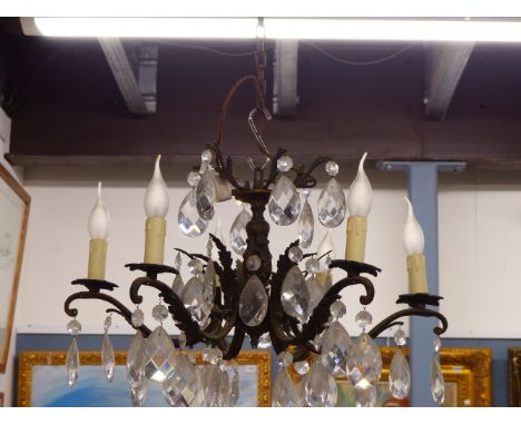 A SIX LIGHT CANDLE FORM CHANDELIER, EACH HUNG WITH A BEAD ABOVE A PEAR SHAPED DROP FROM FOLIATE SCROLLING ARMS