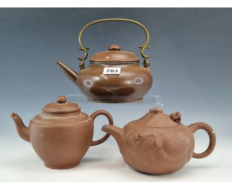 THREE CHINESE YIXING RED WARE TEA POTS, ONE COVER WITH A MOVEABLE DRAGONS HEAD, THE POLISHED EXAMPLE WITH A BRASS OVER SWINGI