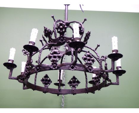 AN IRON CROWN WHEEL SHAPED CEILING LIGHT, THE EIGHT CANDLE FORM LIGHTS ALTERNATING WITH GOTHIC QUATREFOILS ABOVE FLOWER HEADS