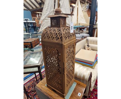A PAIR OF IRON PRICKET CANDLESTICK LANTERNS WITH RING HANDLES CRESTING THE SCROLL PIERCED SQUARE SECTION SIDES.   H 72cms.