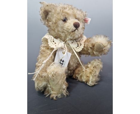 A STEIFF TEDDY BEAR WITH PALE SHAGGY FUR AND WEARING A LACE COLLAR.   H 27cms.