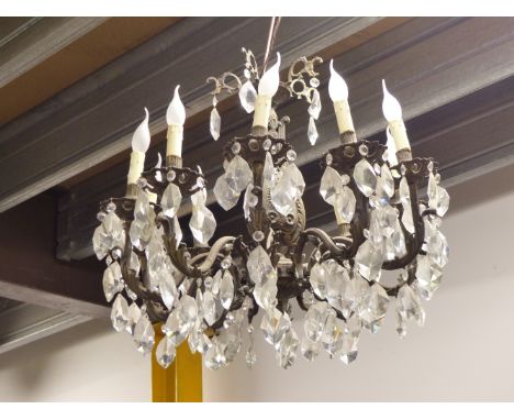 A CHANDELIER WITH TEN CANDLE FORM LIGHTS HUNG WITH DIAMOND SHAPED DROPS FROM FOLIATE SCROLLING ARMS