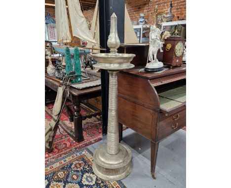 A FLOOR STANDING SILVERED METAL PRICKET CANDLESTICK WITH DISHED DRIP PAN AND CIRCULAR FOOT, THE COLUMN RING TURNED.   H 157cm