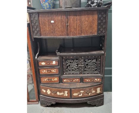 A JAPANESE CABINET WITH A BOW FRONTED TAMBOUR ENCLOSED SHELF TOP OVER DRAWERS WITH INLAID TEA POTS AND PRECIOUS OBJECTS.   W 