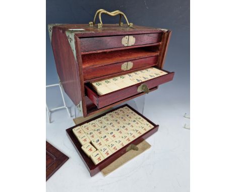 A WOODEN CASED BONE AND BAMBOO MAHJONG SET, THE BRASS MOUNTED CASE.   W 24cms.