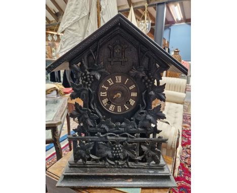 A BLACK FOREST OAK CASED CUCKOO CLOCK, THE MOVEMENT WITH A STRIKE MECHANISM, THE DIAL SURROUNDED BY PIERCED AND CARVED GRAPE 
