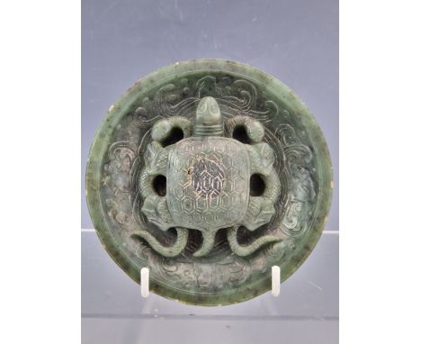 A CHINESE SPINACH JADE TRIPOD BOWL CENTRALLY CARVED IN RELIEF WITH A TURTLE HOLDING DOWN TWO SNAKES, THE CAVETTO OF THE BOWL 