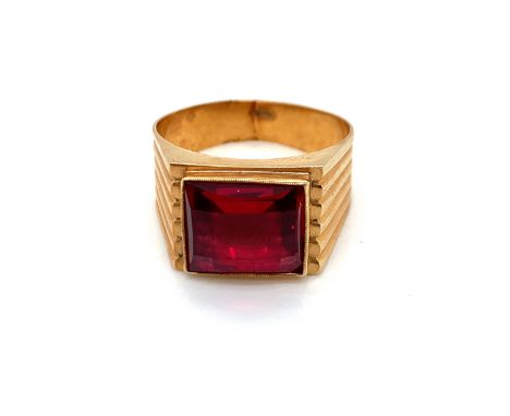 A RED CHEQUERBOARD CUT SYNTHETIC RUBY SET IN A SIGNET STYLE RING MOUNT. UNHALLMARKED, CROWN AND ONE OTHER MARK TO OUTSIDE SHA