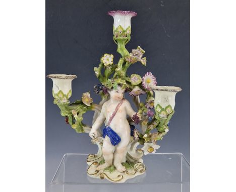 ATTRIBUTED TO 18th C. BOW, A THREE LIGHT CANDELABRUM WITH A PUTTO HARVESTING GRAPES BELOW THE FLOWERING BRANCHES SUPPORTING T