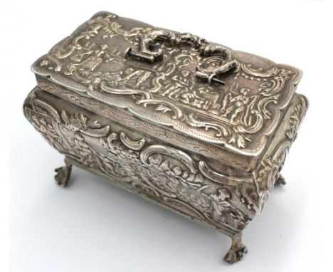 A late 19th century Dutch silver table snuff box, of casket shape with four paw feet and ornate embossed figural or foliate s