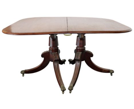 A Regency Mahogany twin pillar dining table, the plain top with rounded corners, plus one extra leaf on turned and ringed pil