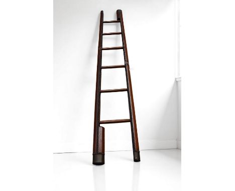 A Vintage 20th century oak and studded hide bound metamorphic ladder, with six steps and when folded showing a single long po