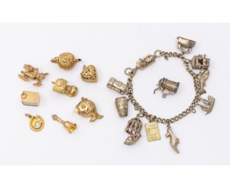 A collection of 9ct gold charms including £10 note, horseshoe, bell, sish, teapot, heart shaped box containing engagement rin