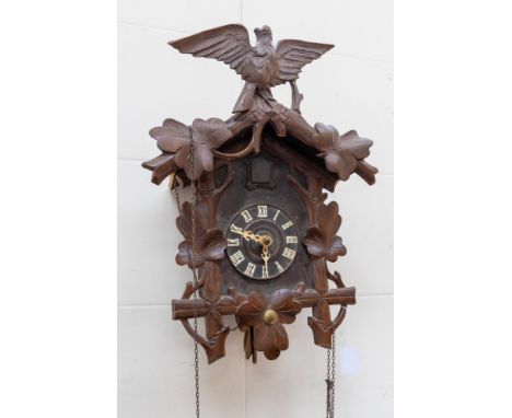 A 20th century carved beech cuckoo clock, together with a pair of weights cast in the form of pinecones