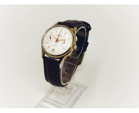 Manual wind mechanical chronograph with date function at six o' clock. Silver dial with blue detailing and red hands. The cas